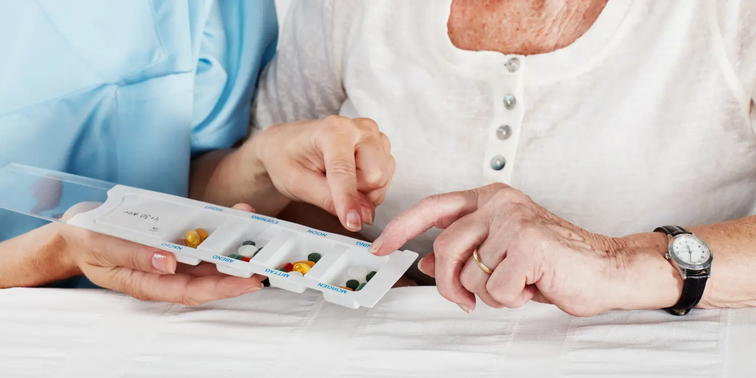 Pflegerin versorgt Seniorin mit Tabletten 